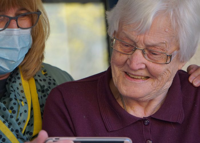Elderly woman and caregiver using KINARE AI on a phone
